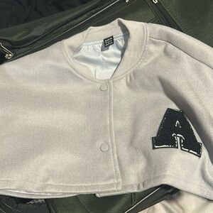 black grey and white cropped varsity jacket with a black A on the left